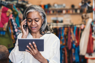 Clothing shop owner using a digital tablet and cellphone