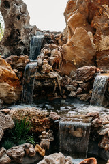 decorative waterfall in the Park with stones. A cozy place with an artificial waterfall in the Park.