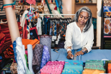 Mature woman marking cloth in her fabric shop before cutting