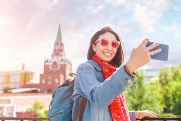 Mixed race woman tourist taking pictures on mobile phone on the backgroung the Kremlin wall tower. Travel to Russia concept