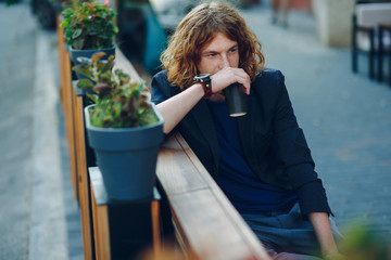 Man resting on a bench with a coffee to go