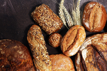 Different kinds of bread and bread rolls on board from above. Kitchen or bakery