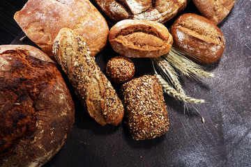 Different kinds of bread and bread rolls on board from above. Kitchen or bakery