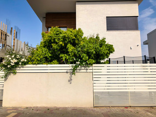 Fototapeta na wymiar Private modern houses with big white fence on the streets in Rishon LeZion, Israel