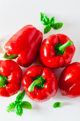 group of red ripe organic bell pepper and fresh basil leaves isolated on white