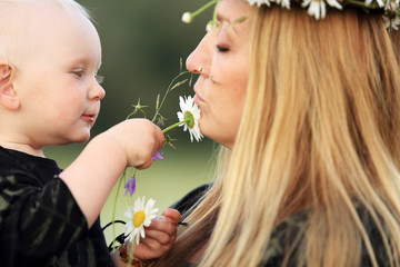 Mała dziewczynka bawi się białymi kwiatkami dotykając twarzy matki. - obrazy, fototapety, plakaty