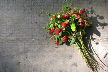 Bouquet of wild strawberry on wooden background. Copy space fot text