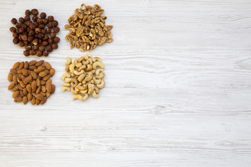 Assortment of nuts on white wooden background. Cashew, hazelnuts, walnuts, almonds. Top view, flat lay. Copy space.