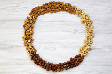Assortment of nuts on white wooden background. Cashew, hazelnuts, walnuts, almonds. Top view, flat lay. Copy space.