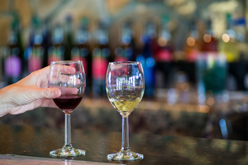 close up two wine glasses at vineyard, tasting reds and whites. bottles in background