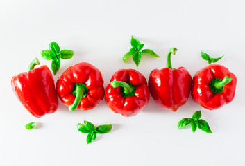 group of red ripe organic bell pepper and fresh basil leaves isolated on white