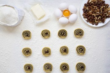 Unbaked cookies with poppy seeds, raisins and nuts on white wooden table. Ingredients for making cookies. Top view, from above, flat lay.