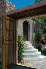 A heavy wooden door with a cross leading to the cemetery of Monemvasia