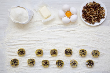 Unbaked cookies with poppy seeds, raisins and nuts on white wooden table. Ingredients for making cookies. Top view, from above, flat lay.