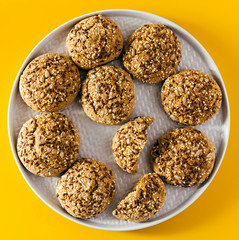 freshly baked oatmeal cookies sprinkled with sunflower seeds, linseed and sesame seeds. healthy pastries in a plate on a yellow background