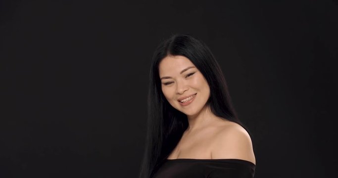 Fashion asian woman wearing alluring black blouse posing on camera. Cared skin concept.