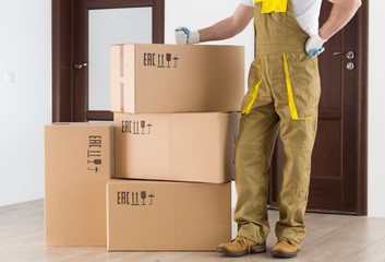 Worker standing near delivered boxes in apartment. Delivery background.