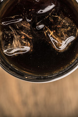 A dark beverage with ice in a glass