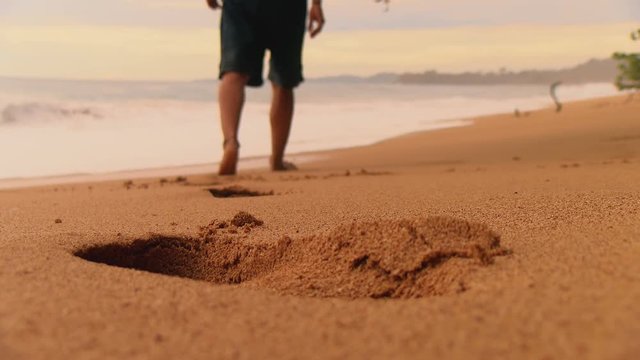 Boy with bare feet leaving his footprints on the sand of a tropical beach.  Caribbean golden unspoiled sandy beach at sunset. Bluff beach in Bocas del Toro islands in the Isla Bastimentos in Panama.