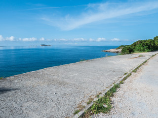 Fototapeta na wymiar concrete road along coastline with sea in the background