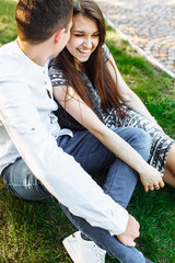 young, happy, loving couple, sitting together on the grass in the Park, and enjoying each other, advertising, and inserting text