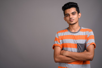 Young Indian man against gray background