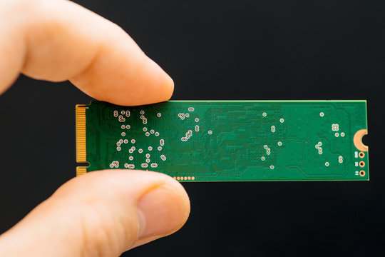 Man hand holding NVME PCIE SSD hard drive disk with high read and write speed - green circuit board 