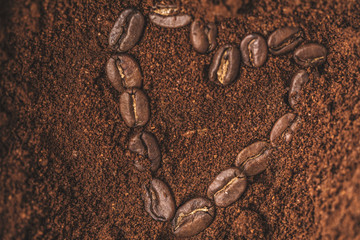 A coffee bean heart in ground coffee