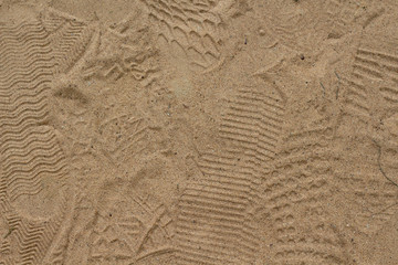 Yellow sand with foot marks photo texture. Shoe sole sand marks. Protecting feet on holiday.