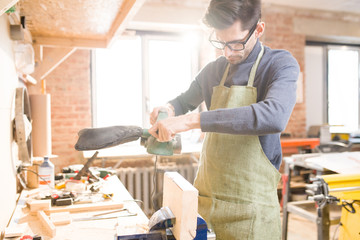 Waist up portrait of focused modern carpenter sanding wood in joinery shop standing at table  in sunlight, copy space