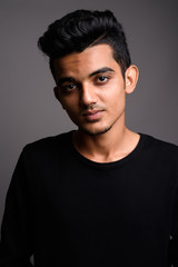 Young Indian man against gray background