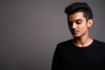 Young Indian man against gray background