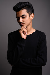 Young Indian man against gray background