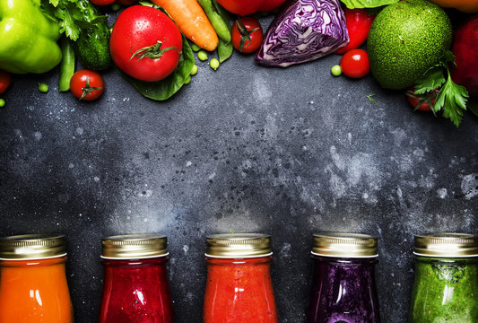 Food and drinks, healthy and useful multicolored vegetable juices and smoothies with ingredients in glass bottles, set on gray background, top view