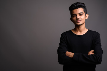 Young Indian man against gray background