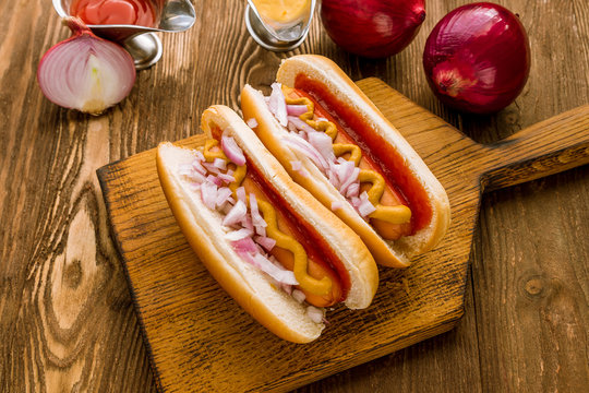Hot dog with ketchup and mustard and red onions