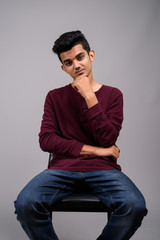 Young Indian man against gray background