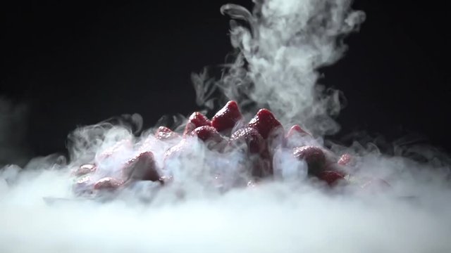 Liquid nitrogen is scattered around a pile of strawberries on a plate.