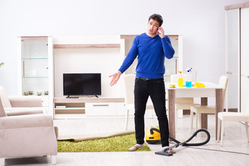 Young man vacuum cleaning his apartment