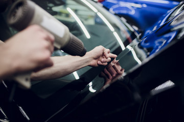 Worker hands installs car paint protection film wrap hood