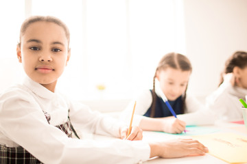 Portrait of African schoolgirl sitting at hte desk and writing