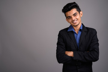 Young Indian businessman against gray background