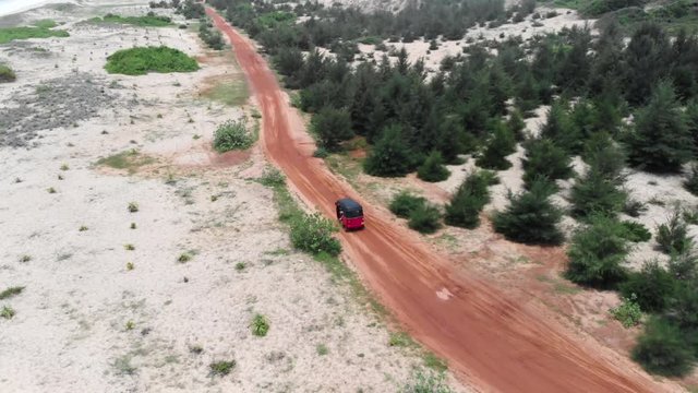 Aerial drone flight over a auto-rickshaw in a red sand road of the south of SRI LANKA. As a tourist you can hire one and explore the island. Shot in 4k.