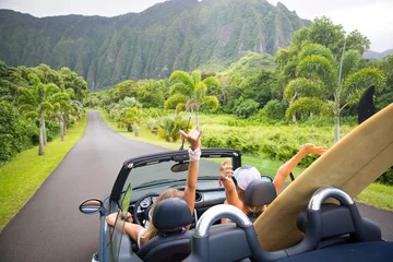 Fototapeten Road trip travel - girls driving car in freedom. Happy young girls cheering in convertible car on summer Hawaii vacations. © RightFramePhotoVideo