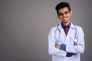 Young Indian man doctor against gray background