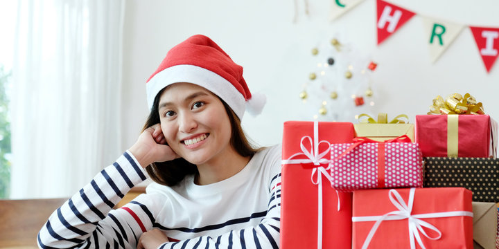 Young cute asian girl smiling while sitting with Christmas gift boxes at Christmas celebration party