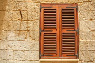 Fototapeta na wymiar A shuttered window of a historic building with shutters.