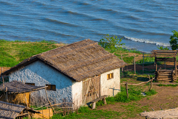 Old traditional white croft cottage with thatched roof, with sea in the bay. Concept of isolated beauty, conservation, building with nature