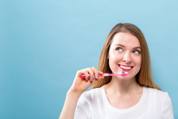 Young woman holding a toothbrush on a solid background