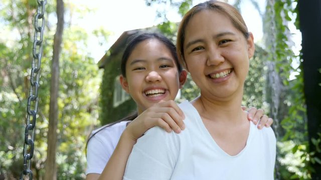 4K Slow motion Asian mother and daughter smiling and looking for the camera in the park together